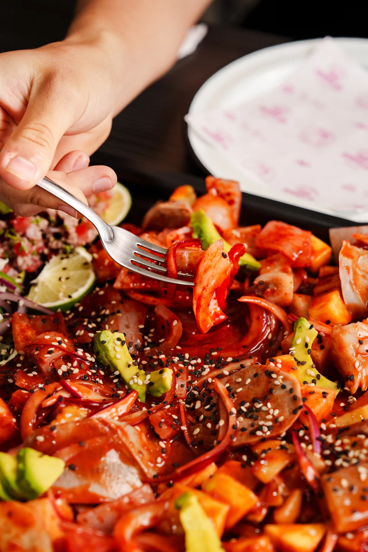 Charola de mariscos preparados con una mano tomando un bocado con tenedor