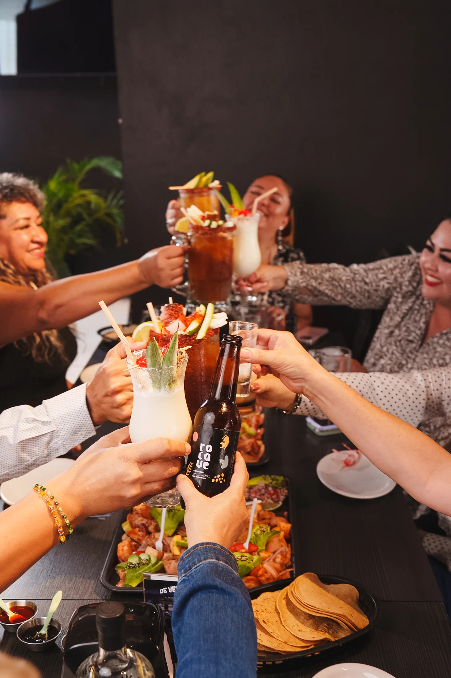 Foto real: brindis de grupo con cerveza Rocave, micheladas y tostadas de mariscos en Del Abuelo